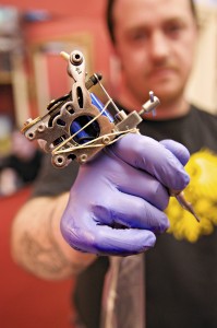 A tattoo artist holding his tattoo gun
