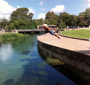 The Sun God of Texas State diving into a river