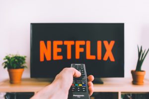 free stock image from unsplash person with remote pointing at tv with netflix logo in an article shows from the 2010s