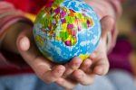 A hand holding a small globe in an article about third culture kids