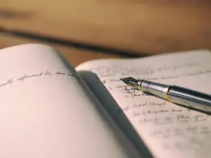 This article discusses the struggle and experience that comes along with success utilizing the power of writing and authors as an outlet for this success. The image above, showing a pen on paper, depicts this idea.