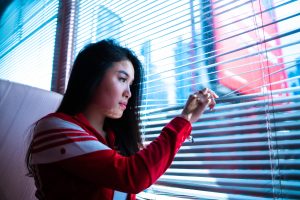 Photo of woman in quarantine looking out a window