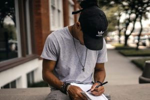 In an article about writing fan fiction, and person sitting and writing in a journal outside