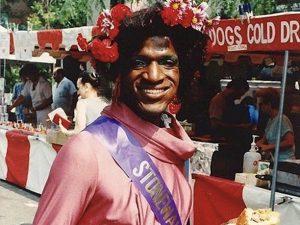 Marsha P. Johnson posing with flowers in her hair and a sash that reads "Stonewall"; black women activists