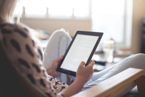 In an article about whether you should finish a book you don't like reading, Woman reading on her Kindle.