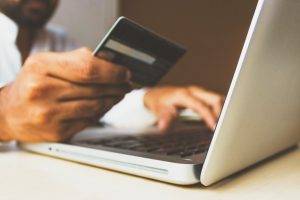 Image of a person at a laptop with a credit card in hand, in an article about using apps for informed shopping