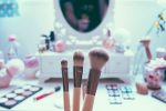 in an article about pretty privilege, a photo of makeup brushes in front of a makeup mirror