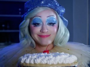 Katy Perry dressed as clown holding up a pie in the music video to her new album titled 'Smile'