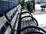 In article about homeless people and hostile architecture, a photo of a bench with extra armrests installed