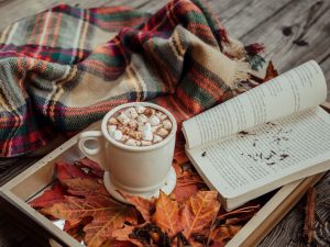 An image of a book on top of fall leaves for an article on Halloween book recommendations.