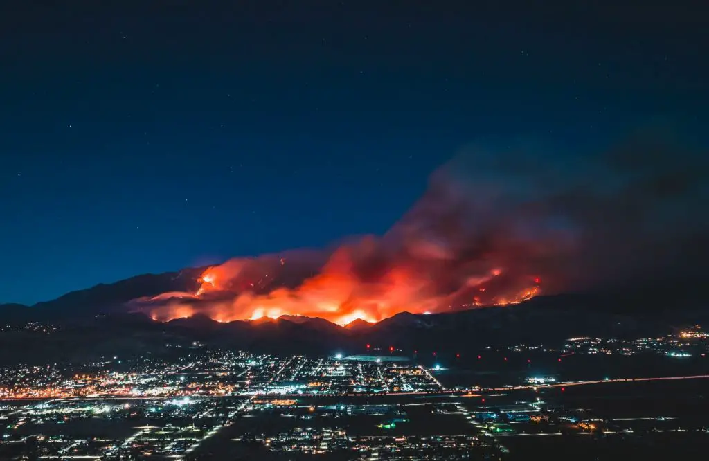 In an article about West Coast wildfires. The image is of a fire behind a California town.