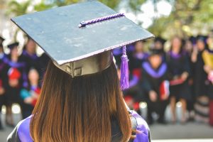 An image of a woman in a graduation gown and hat for an article on first-generation college students.