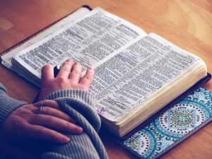 A photo of a woman, perhaps a Christian influencer, reading from the Bible.