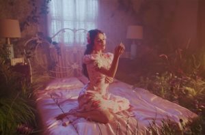 selena gomez sitting on a bed surrounded by flowers in the de una vez music video
