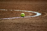 In an article about sports, a photo of a softball on a dirt field