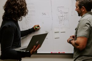 Two people at a whiteboard in an article about random success