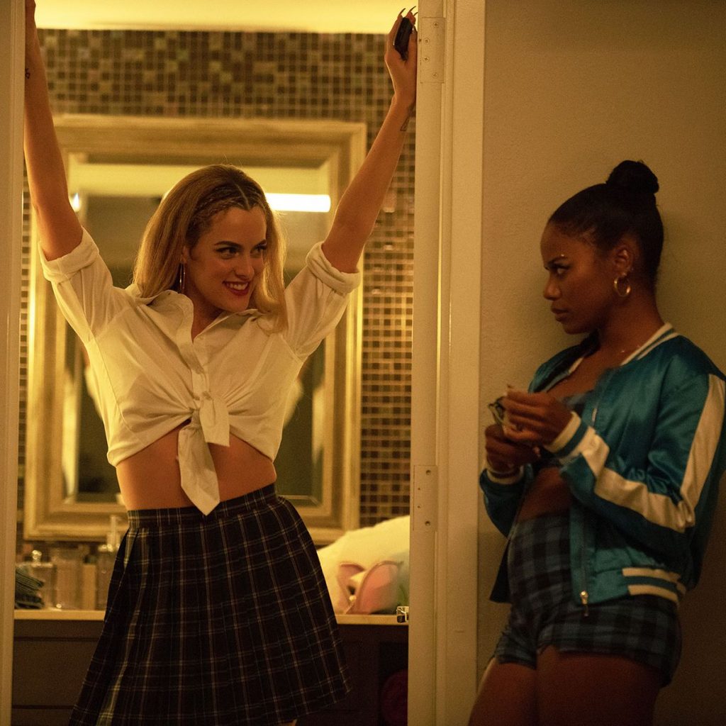 In an article about "Zola," actress Riley Keough stands in a bathroom doorway while Taylour Paige looks at her from the side.