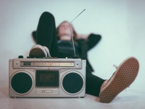 To represent an earworm, a young person is pictured listening to music on an old cassette player.