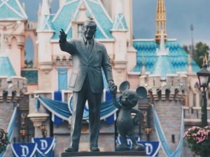 In an article about Disney live-action remakes, a statue of Walt Disney and Mickey hold hands before a castle.