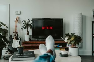 Image of a person with their feet propped up in front of a TV with a Netflix screen