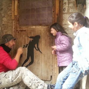 Muralist David De La Mano showing a work in progress to a little girl