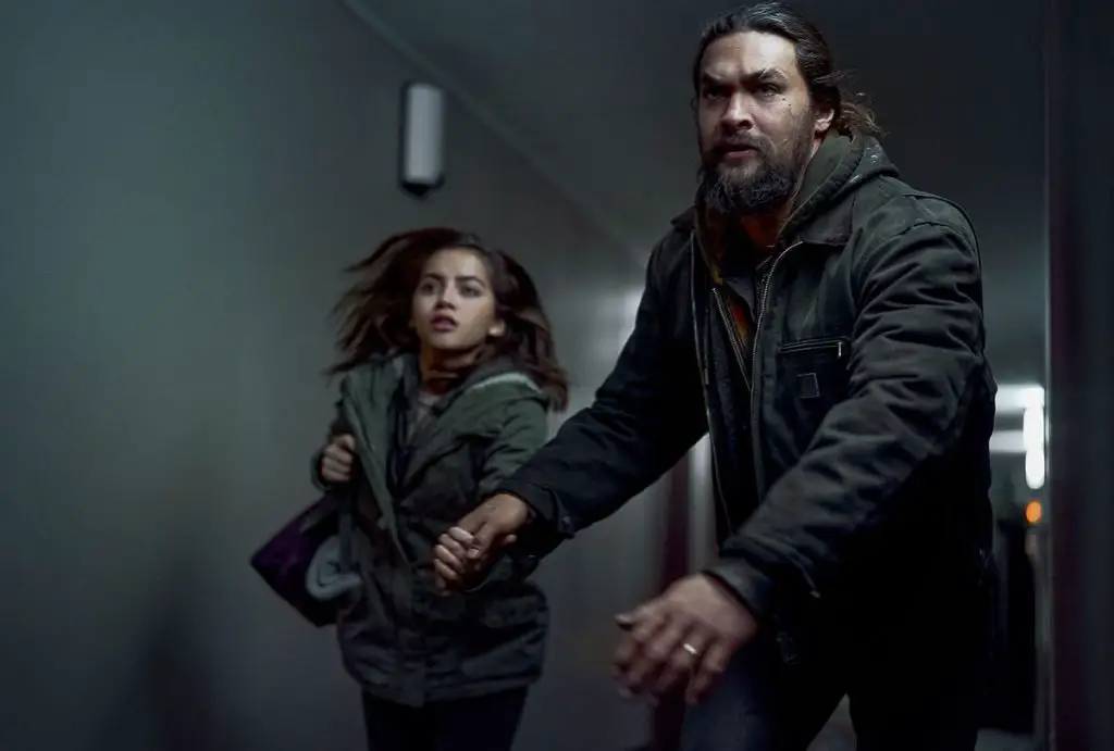 In an article about Sweet Girl, Jason Momoa pulls Isabela Merced down a dimly lit hallway.