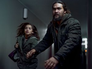 In an article about Sweet Girl, Jason Momoa pulls Isabela Merced down a dimly lit hallway.