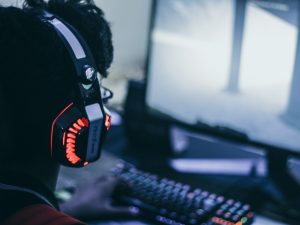 In an article about gaming a person wearing headphones sitting in front of a computer