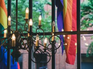 In an article about lesbian bars, a chandelier in front of a window looking out to pride flags
