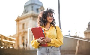 A woman smiles in front of a college building for an article about being an introvert in college.