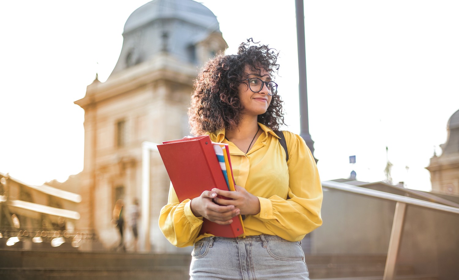 A woman smiles in front of a college building for an article about being an introvert in college.