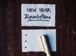 Photo of a piece of lined paper with "New Year's Resolutions" written at the top and a pen beside it.