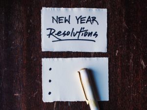 Photo of a piece of lined paper with "New Year's Resolutions" written at the top and a pen beside it.