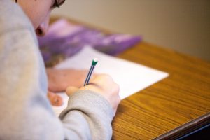 in an article containing study tips, someone writing on a piece of paper on their desk