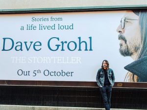 Dave Grohl standing in front of ad for memoir The Storyteller