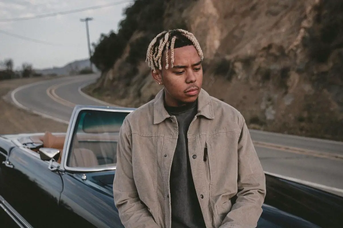 in an article about album from a birds eye view, cordae sitting on a convertible
