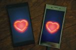 Two smartphones side by side with images of neon heart on both screens.