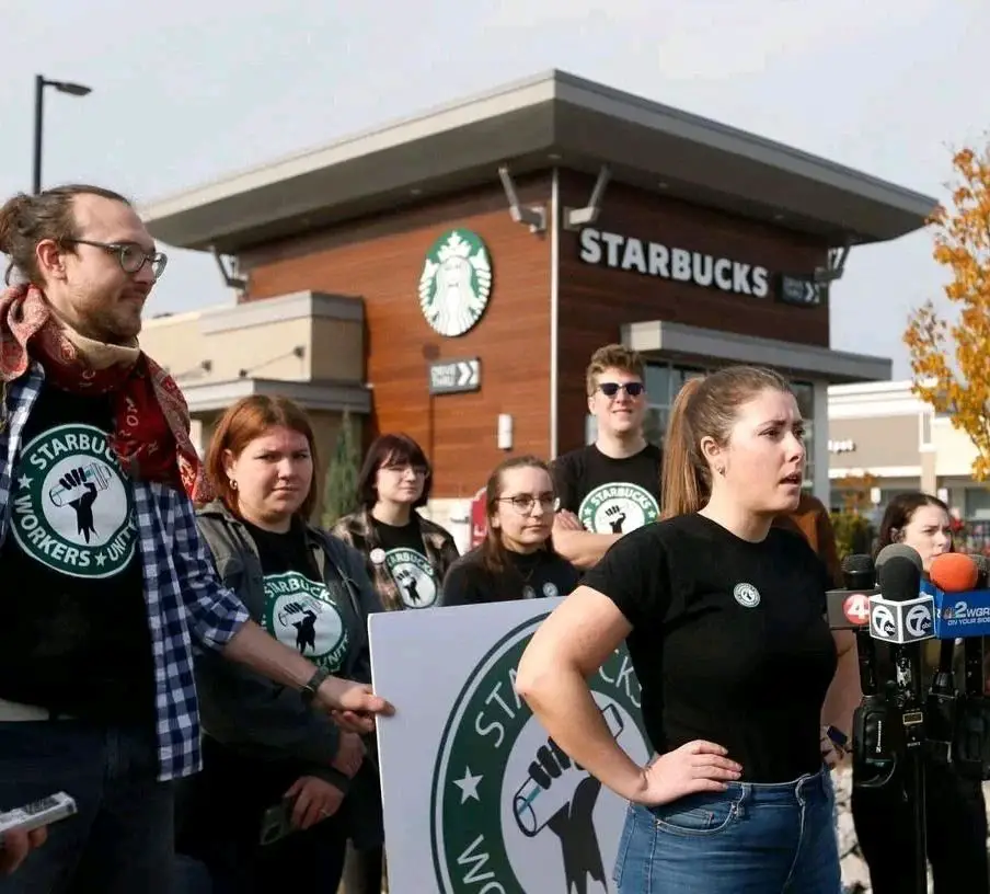 Starbucks union workers striking outside a store with posters and tshirts