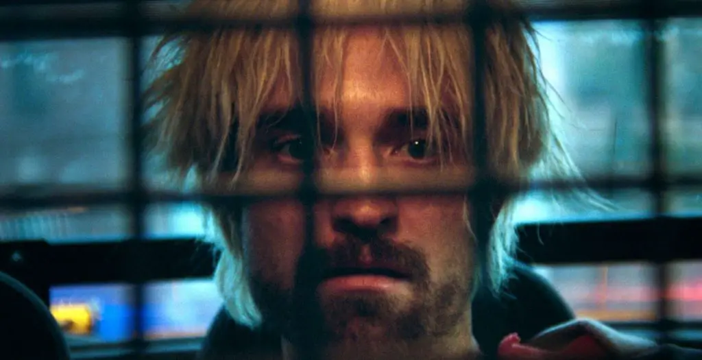 Pattinson in the back of a cop car in his film Crime Caper.