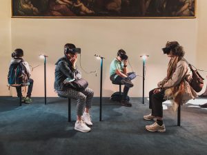 Four people sitting on stools while using virtual reality headsets
