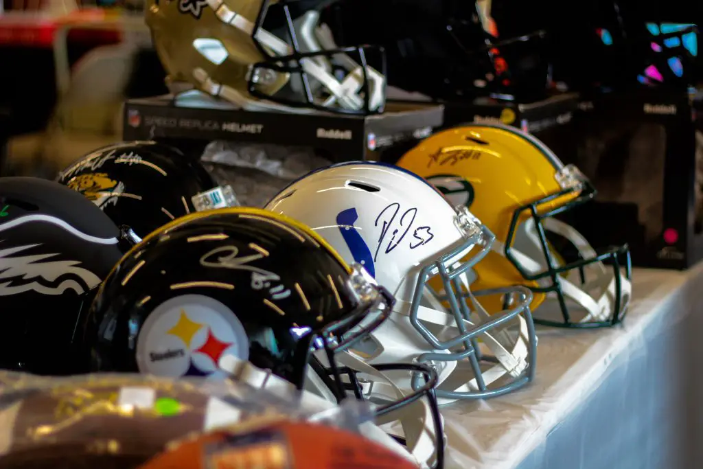 Various American football helmets lined up on a shelf
