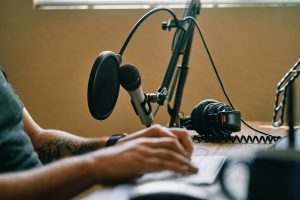 someone at a microphone in an article about indie podcasts