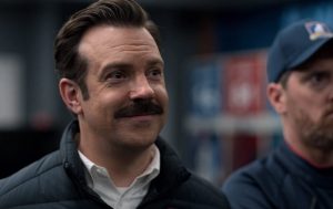 In an article about the TV show "Ted Lasso" and its portrayal of mental health, a screenshot of Ted Lasso smiling.