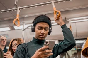 in an article about fake news, someone looking at their phone on the subway