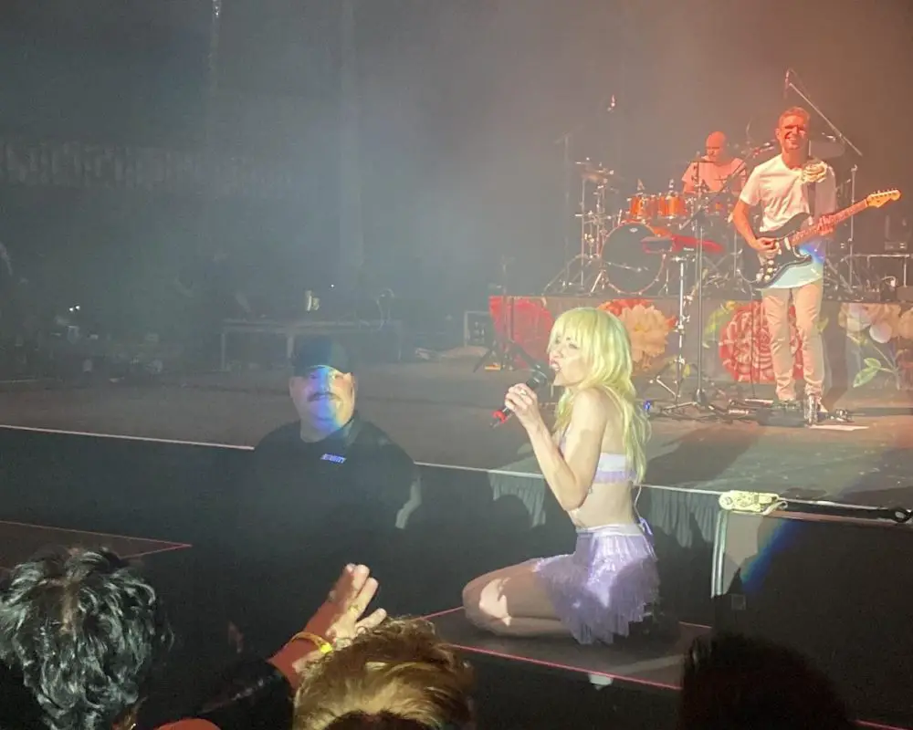 Carly Rae Jepsen crouching on a platform during a performance