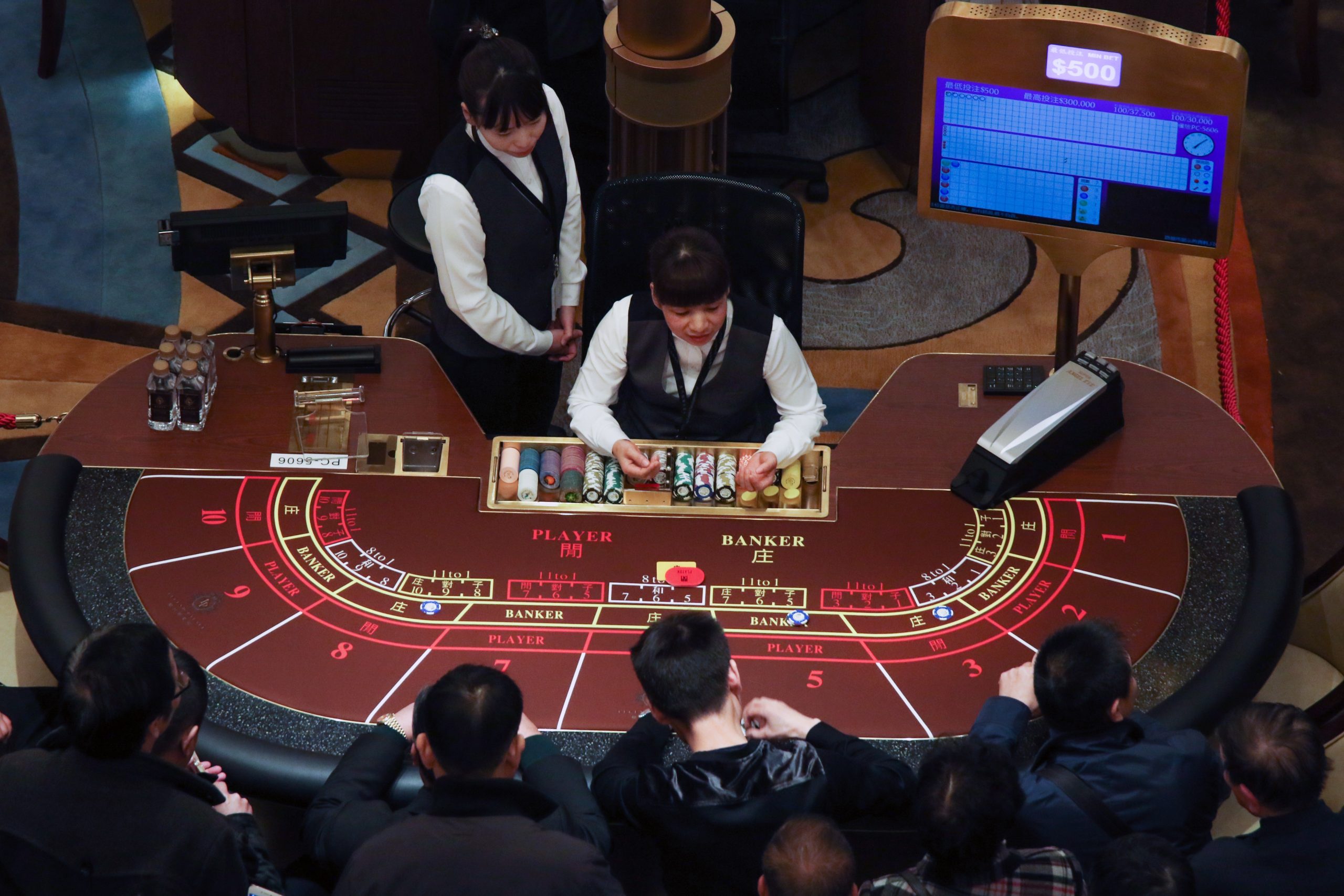 a table in a casino with two casino workers and few gamblers