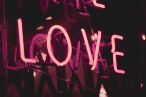 In an article about the 'fake love' trope, an image of a pink neon sign that reads LOVE.