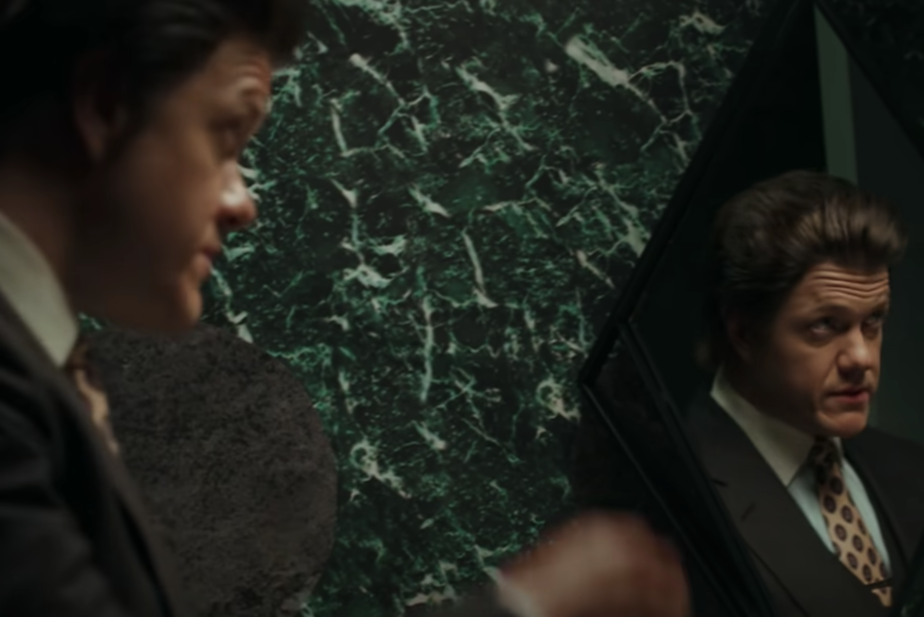 A screenshot from Mercury: Part 2 song Bone's music video showing a man staring into a mirror absentmindedly.