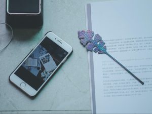 A picture shows social media book accounts on a phone alongside a book and bookmark