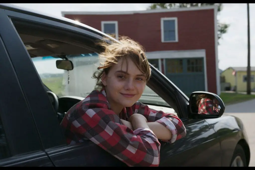 A screenshot from CODA shows a young girl smiling while leaning out of the window of a black truck